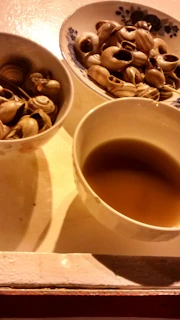 A steaming pot of traditional African soup simmering with snail meat and spices.