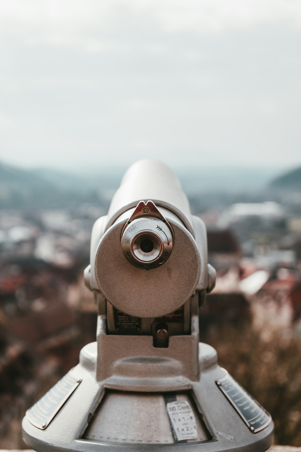 white telescope in front of city buildings during daytime