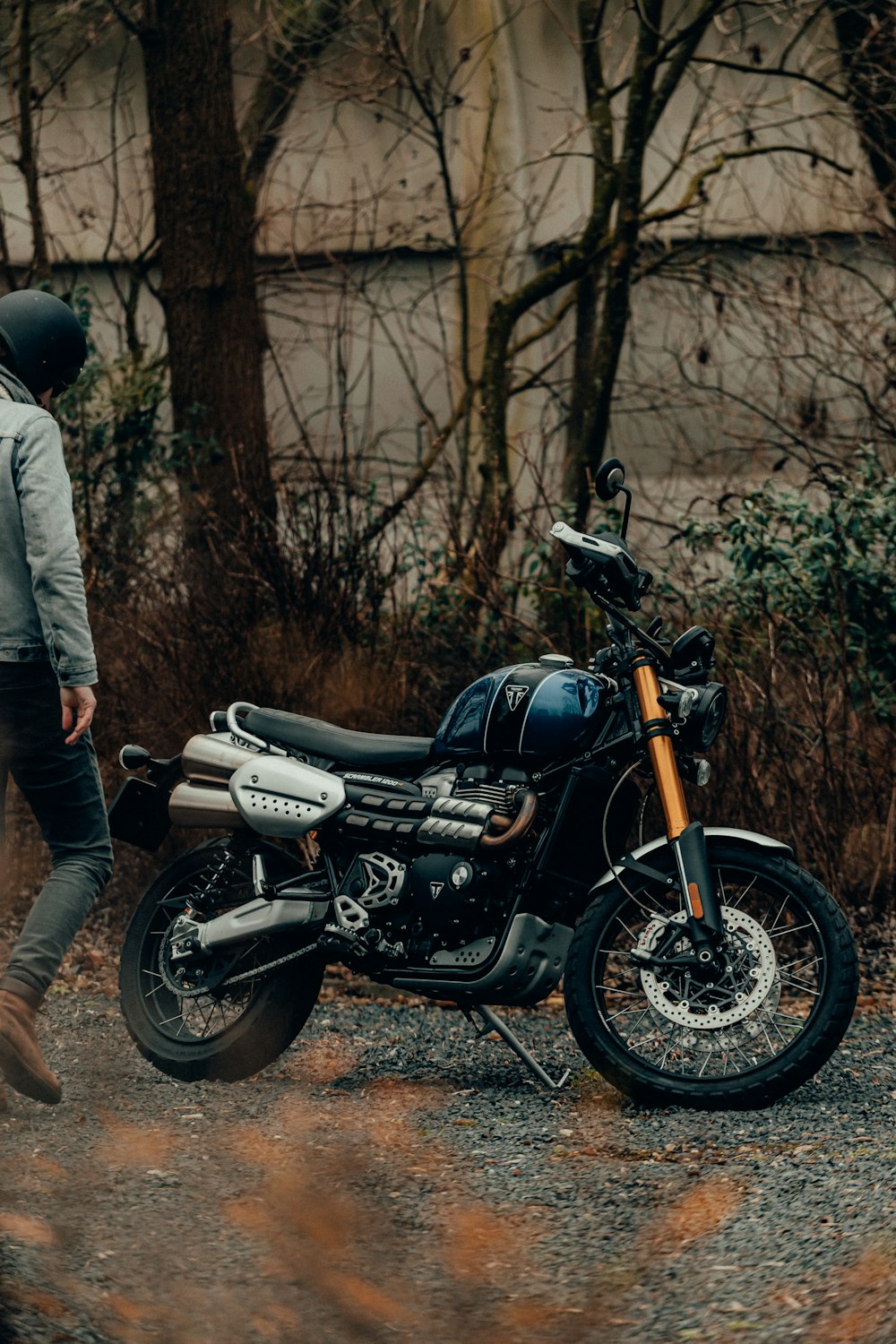 Hombre en chaqueta gris de pie junto a motocicleta negra y gris