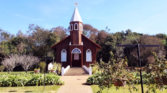 white and black church near green trees under blue sky during daytime in Carambeí Historic Park Brasil