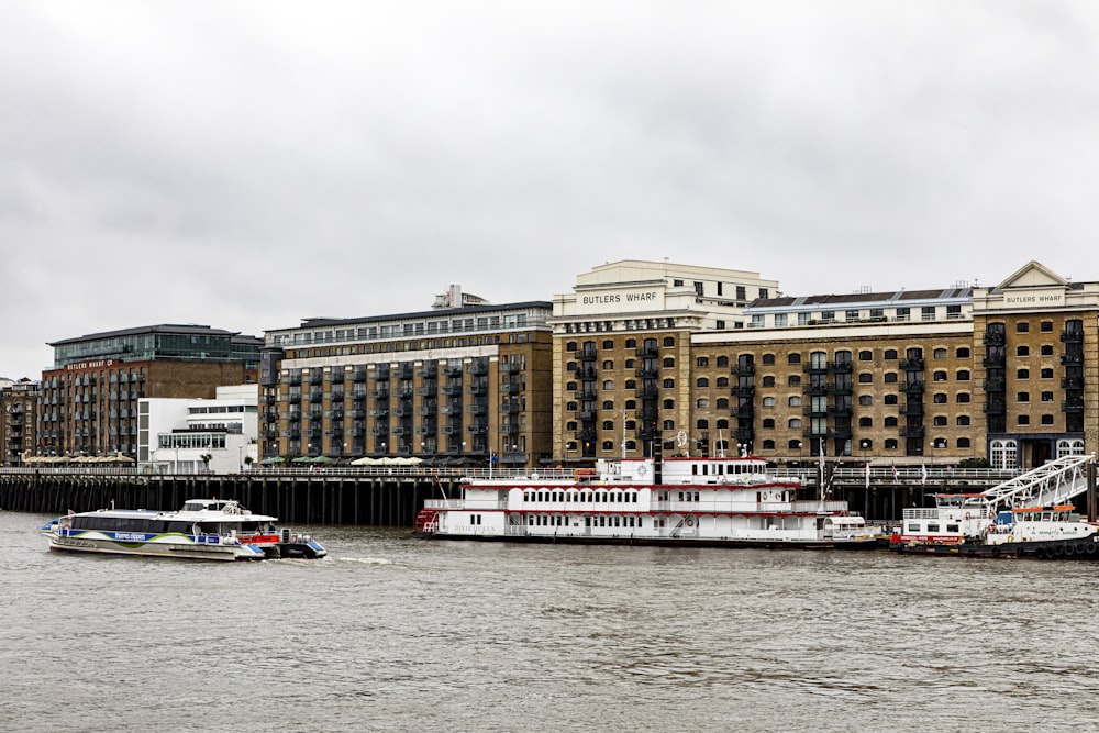 Bateau blanc et rouge sur l’eau près d’un bâtiment en béton brun pendant la journée