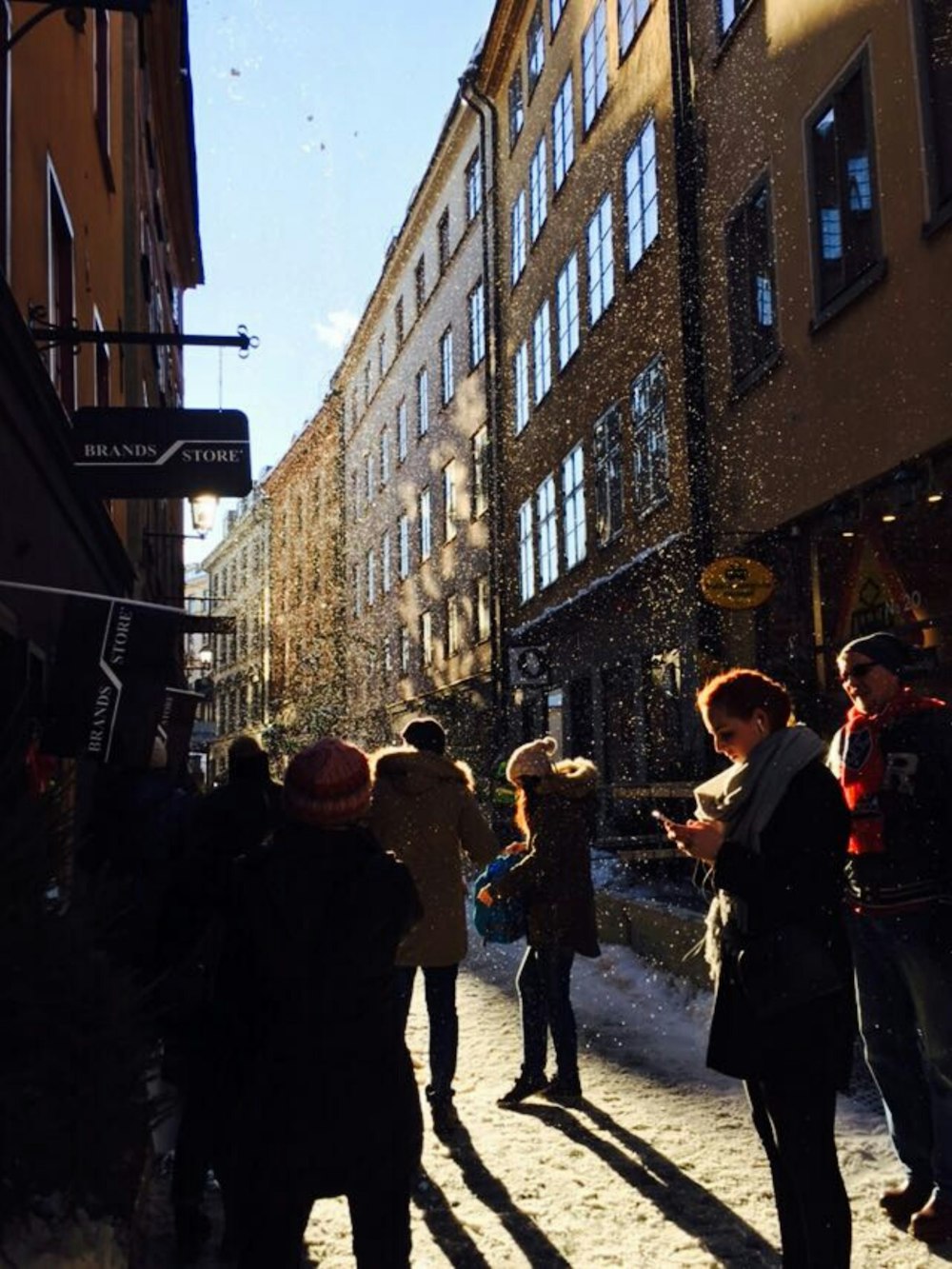 a group of people walking down a street next to tall buildings