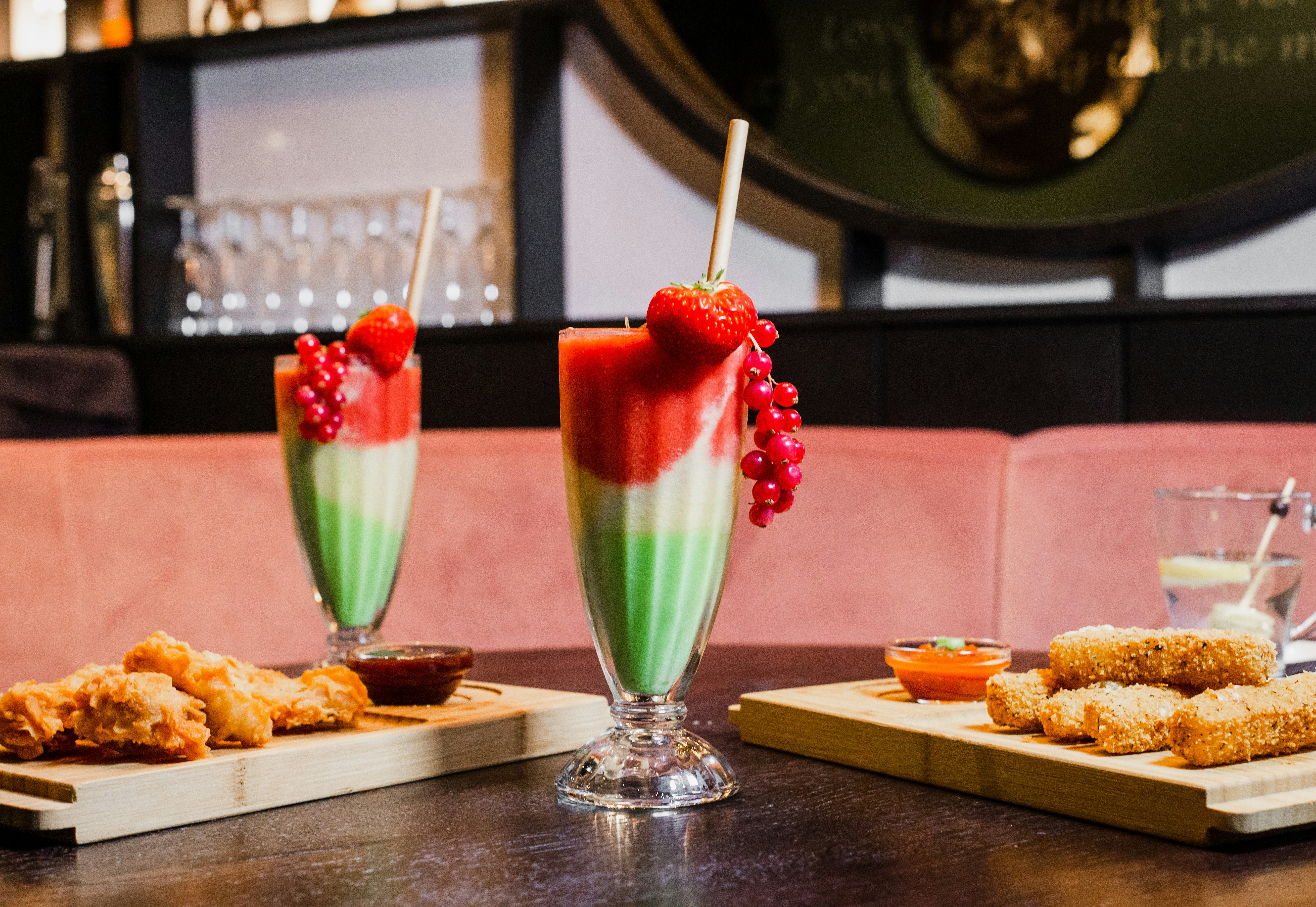 Red and green layered drinks with snacks on boards