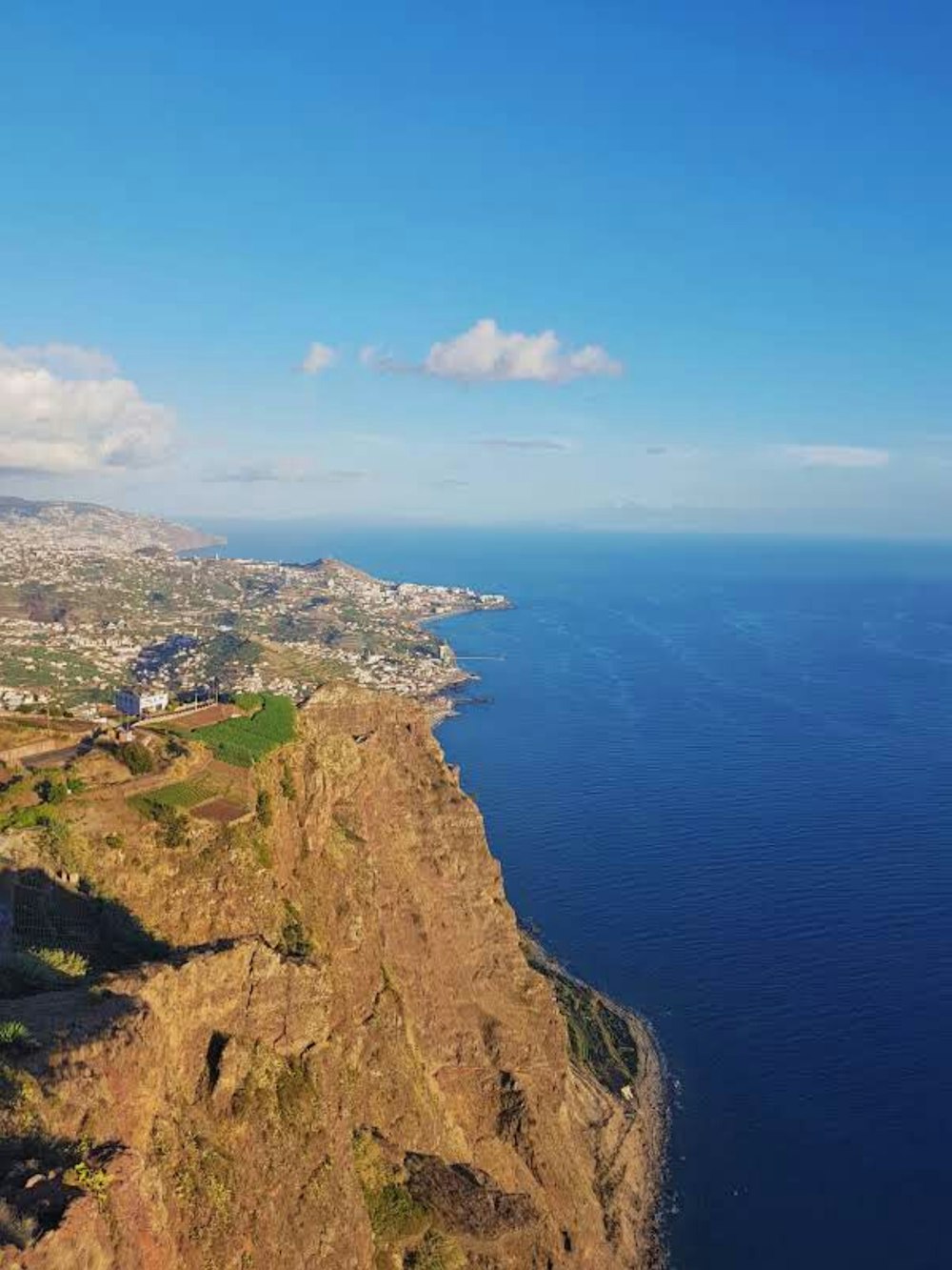 Vue aérienne de la montagne verte et brune à côté de la mer bleue sous le ciel bleu pendant la journée