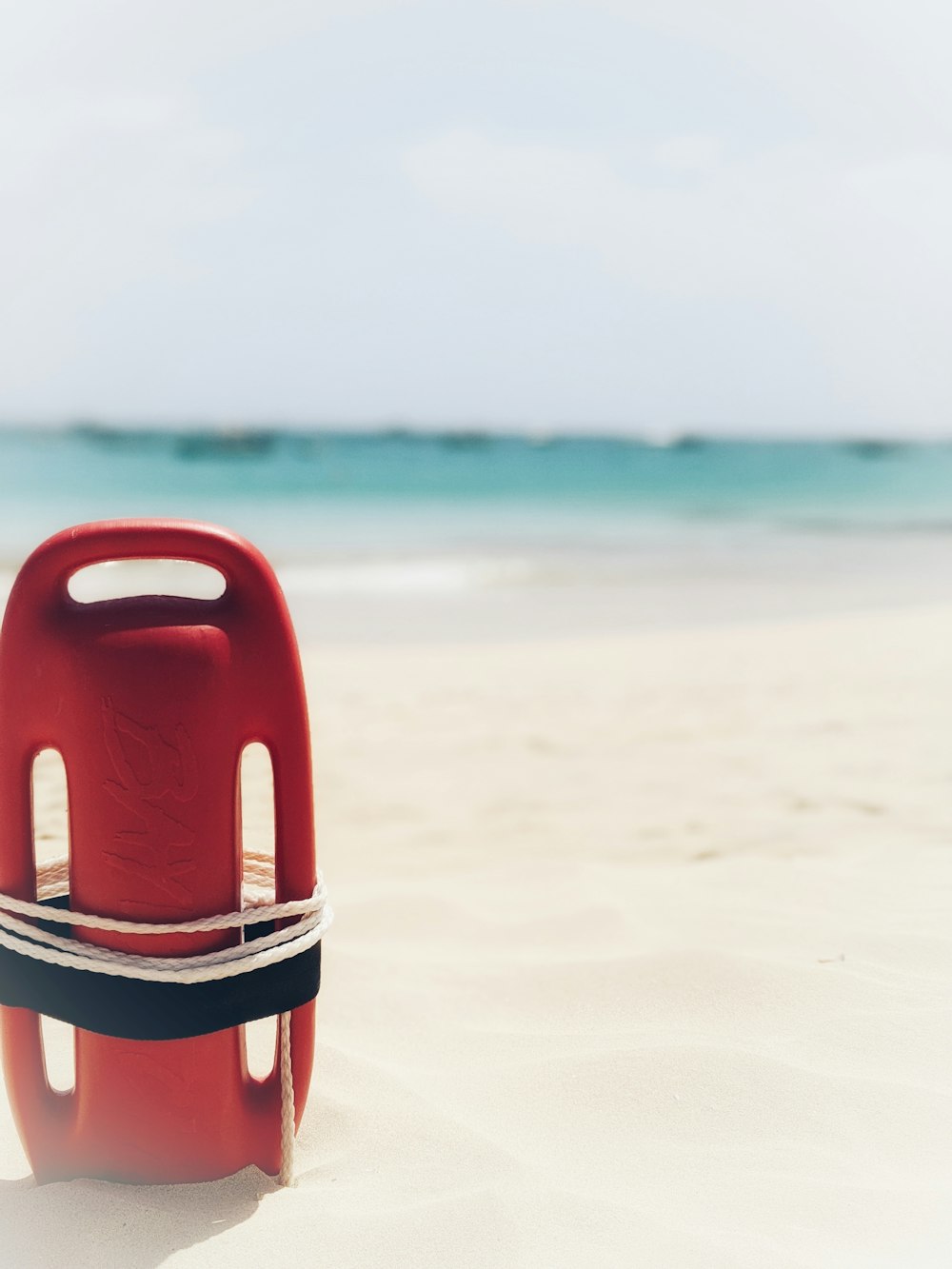 anello di nuoto rosso e bianco sulla spiaggia durante il giorno