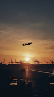 silhouette of airplane flying over the people during sunset
