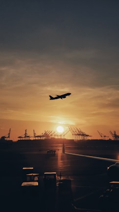 silhouette of airplane flying over the people during sunset