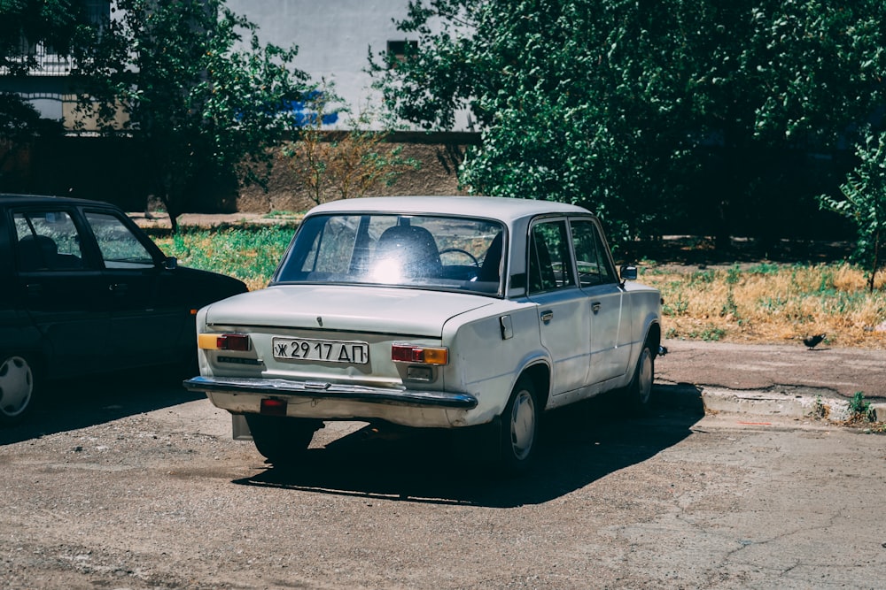 blue sedan parked near green trees during daytime