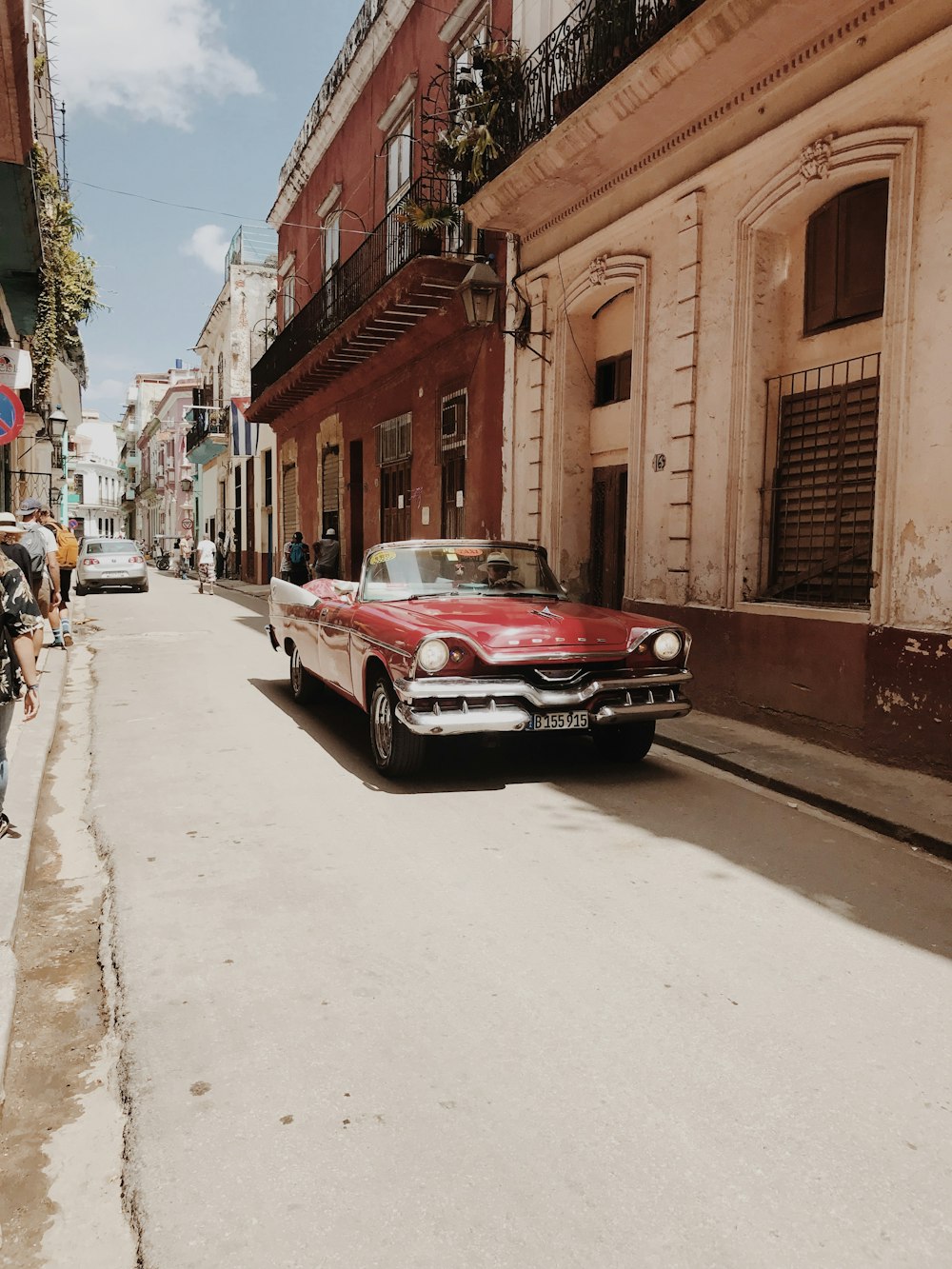 red car parked beside brown concrete building during daytime