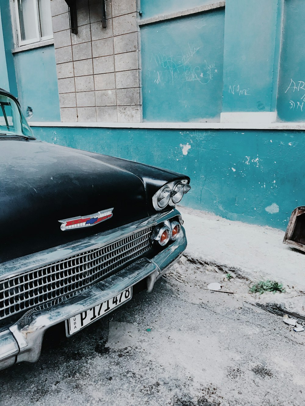 black car parked beside blue concrete building