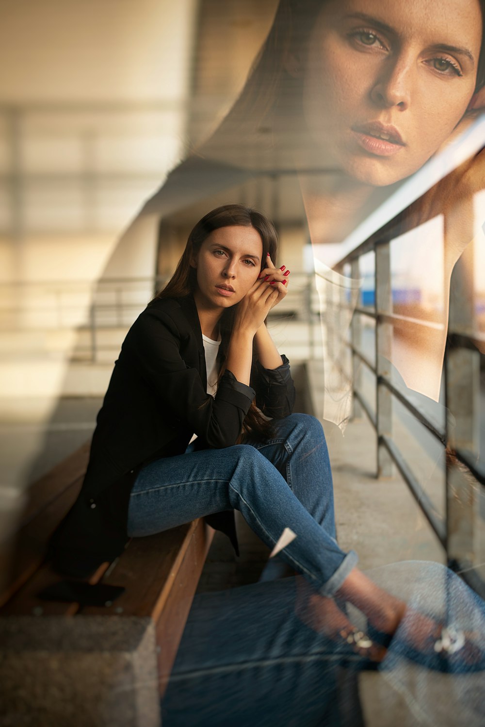 woman in black long sleeve shirt and blue denim jeans sitting on glass window