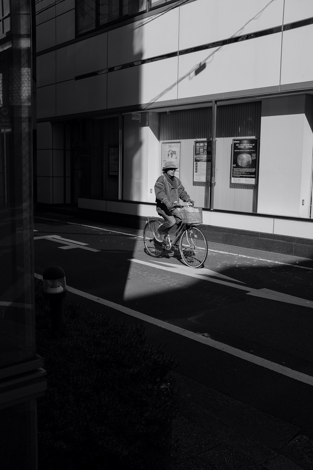 grayscale photo of man riding bicycle on road