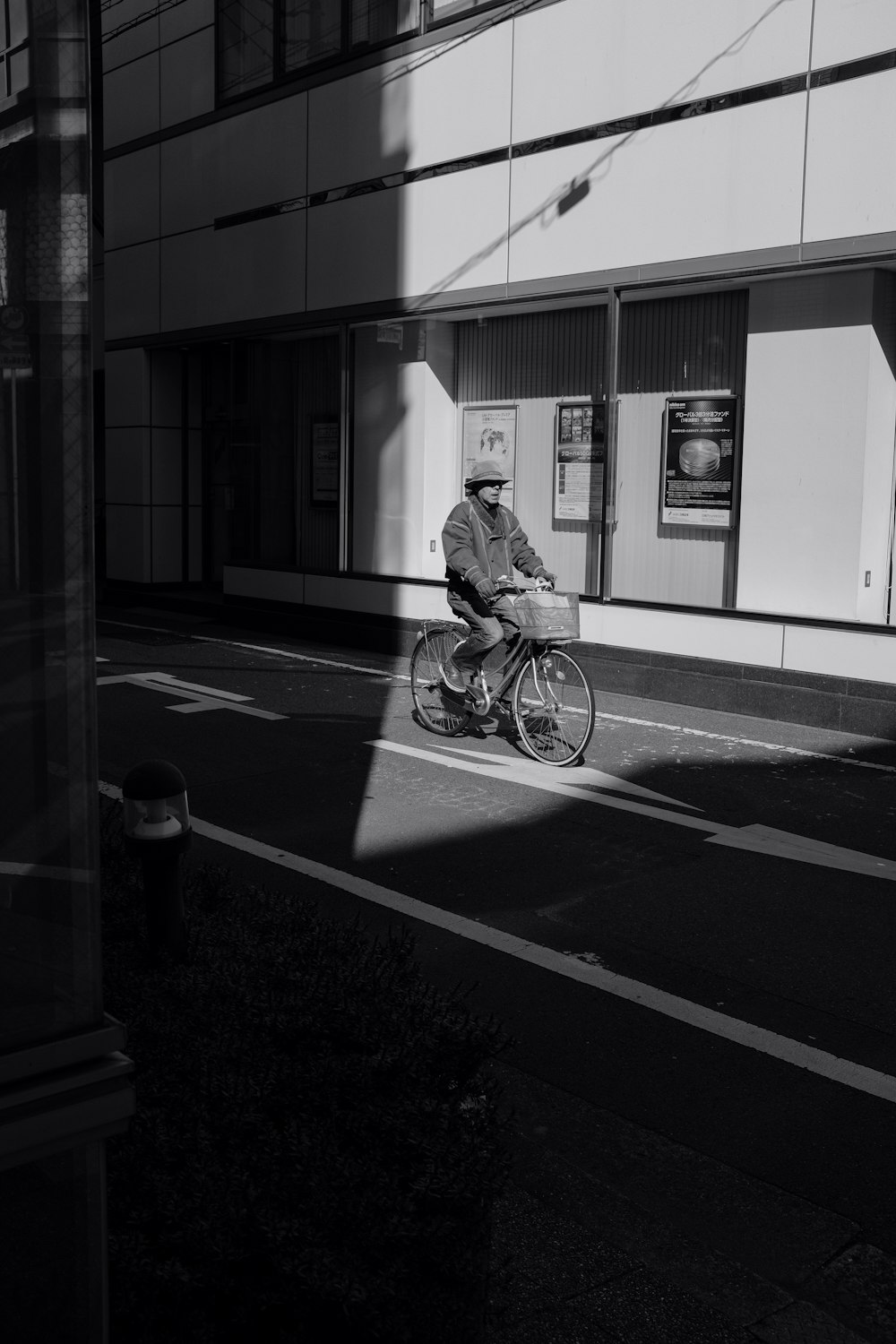 grayscale photo of man riding bicycle on road