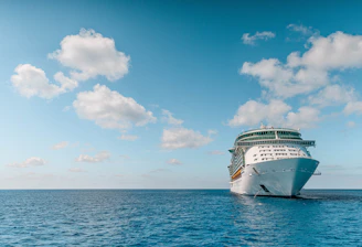 white and blue ship on sea under blue sky and white clouds during daytime