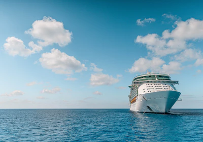 white and blue ship on sea under blue sky and white clouds during daytime