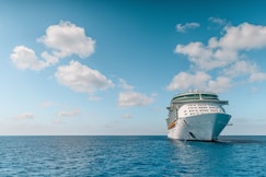 white and blue ship on sea under blue sky and white clouds during daytime