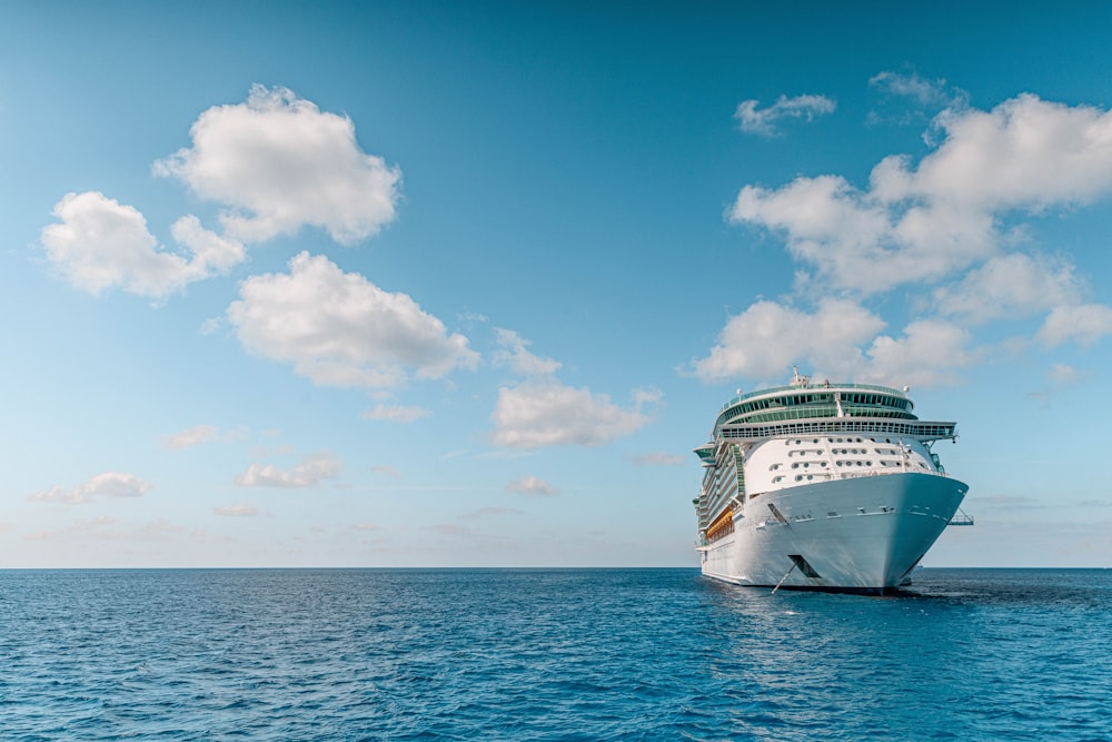 weißes und blaues Schiff auf See unter blauem Himmel und weißen Wolken tagsüber