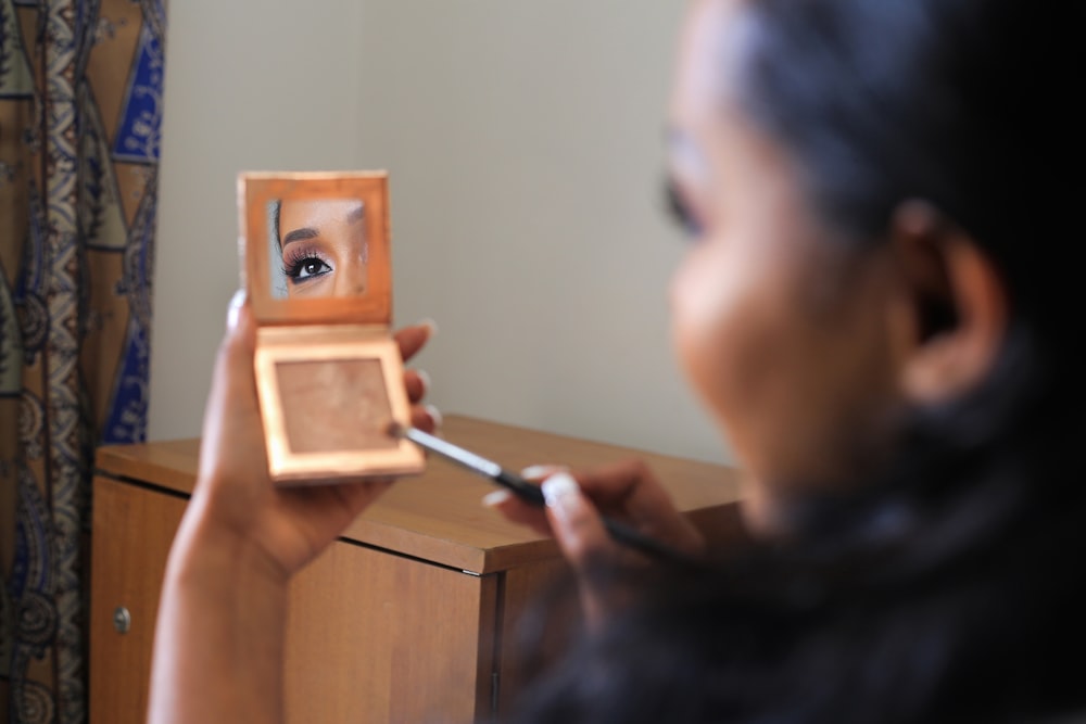 woman holding black pen and brown wooden cube