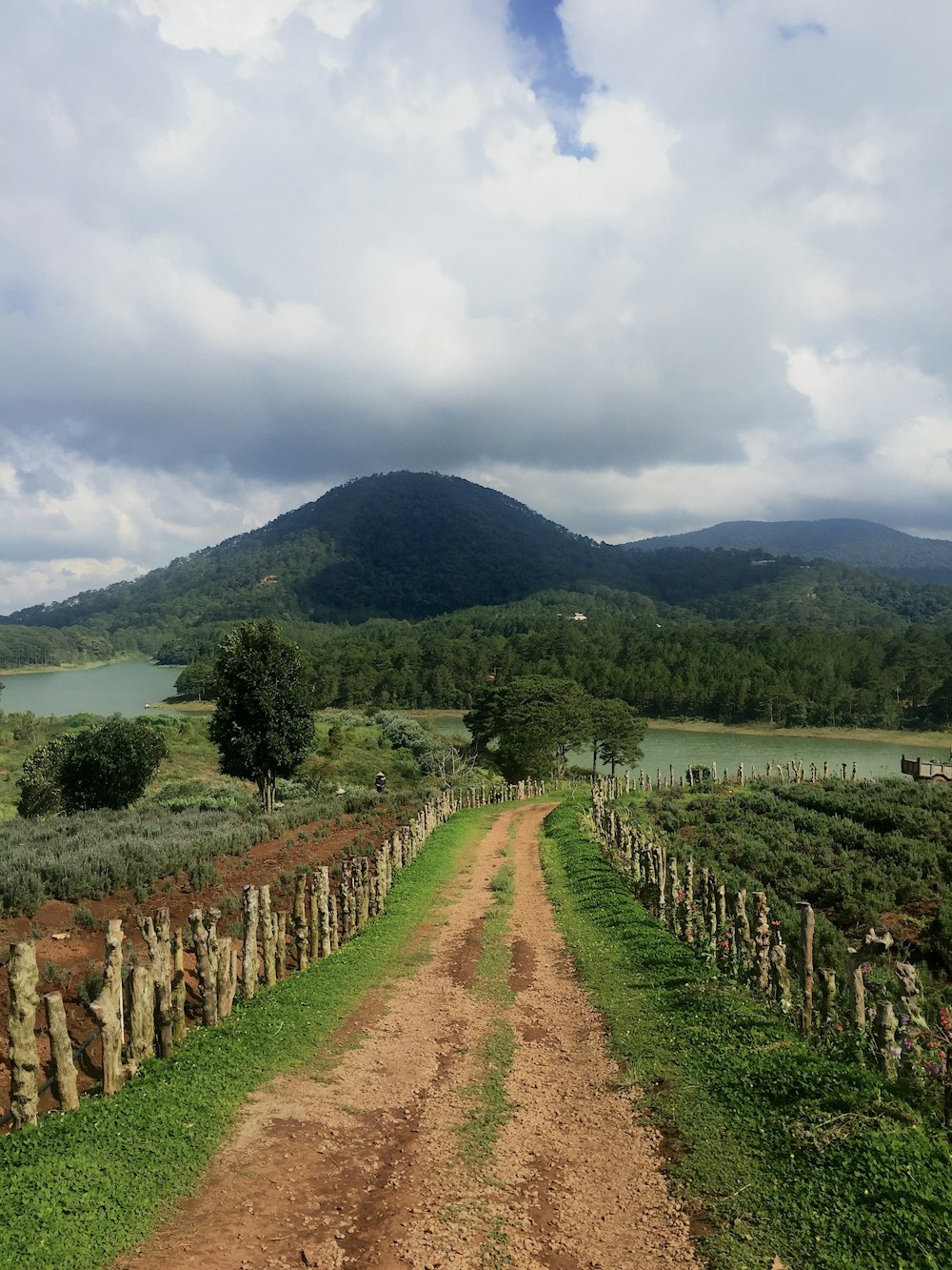 green grass field near mountain under white clouds during daytime