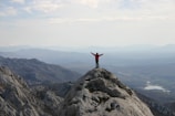 A person standing on a mountain peak, arms raised in triumph.