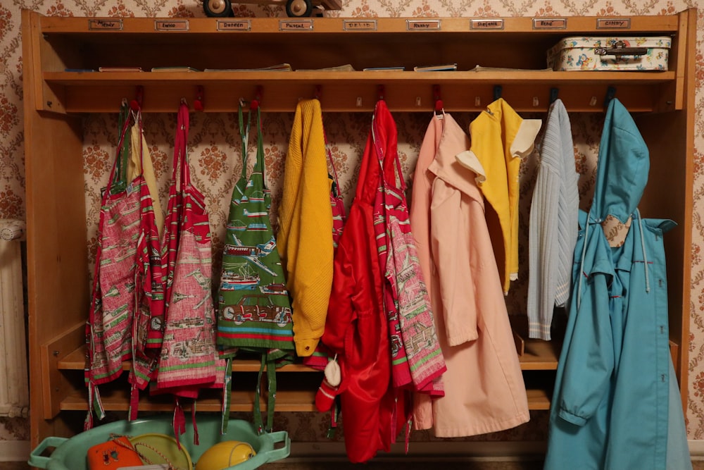 assorted clothes hanged on brown wooden cabinet