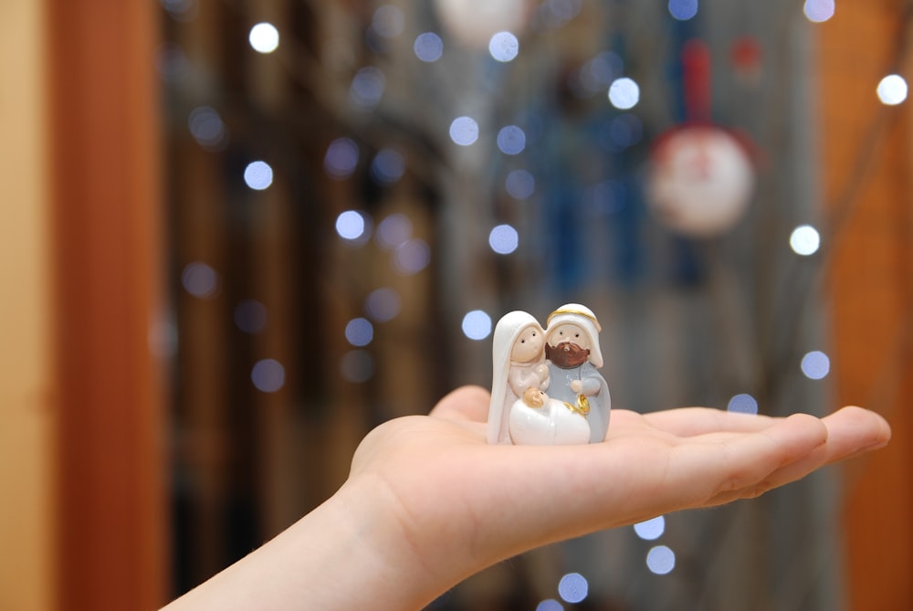 person holding white ceramic figurine