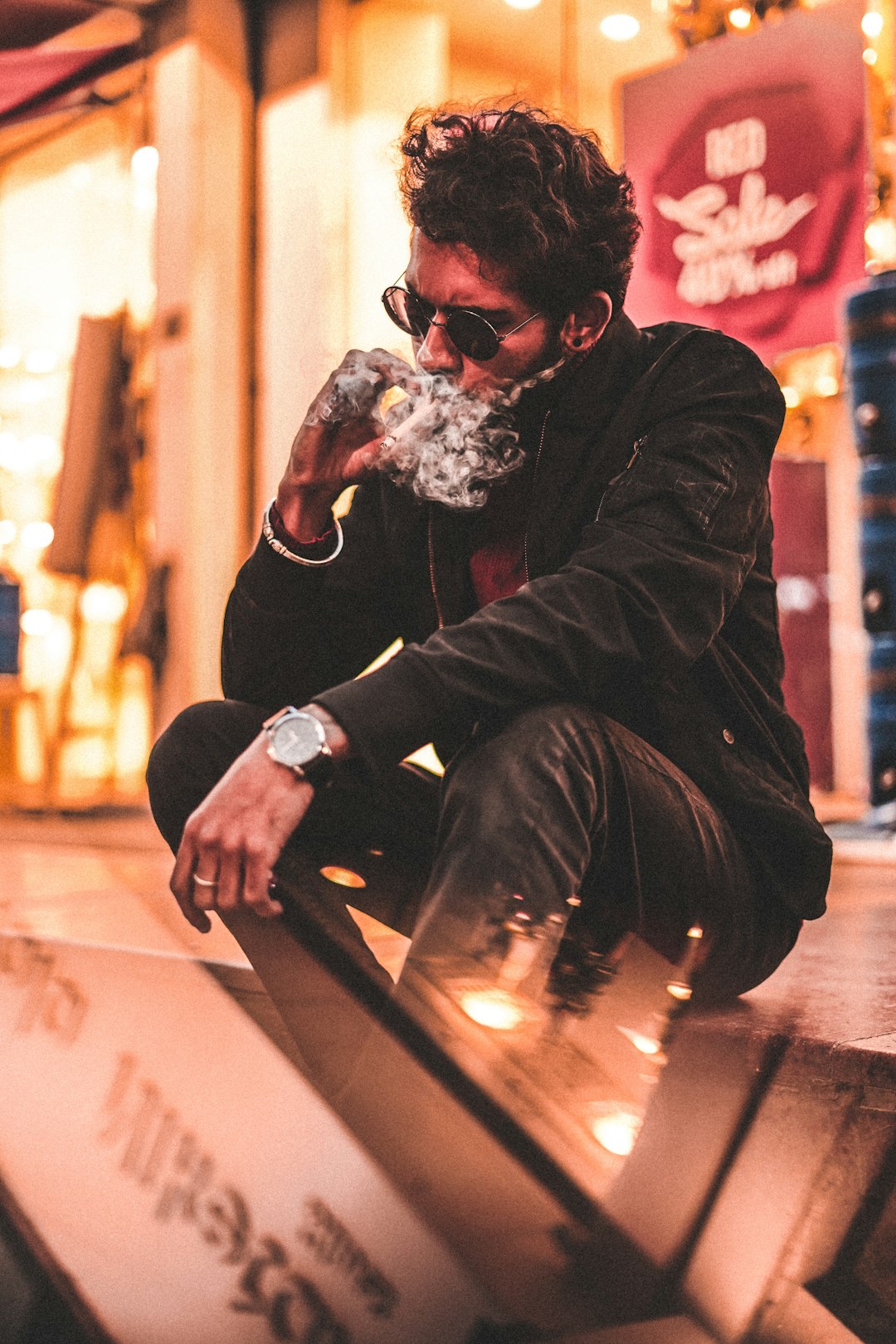 man in black jacket and black pants sitting on brown wooden bench