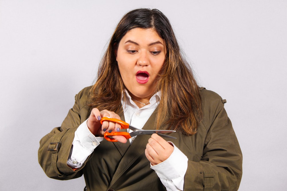 woman in brown jacket holding orange plastic spoon