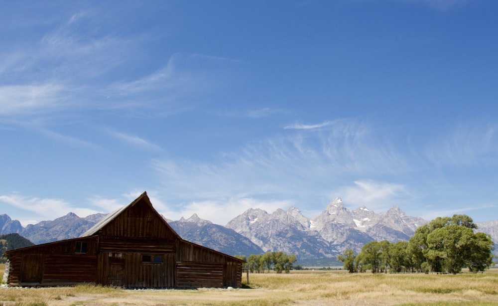 brown wooden house near snow covered mountain under blue sky during daytime