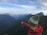 person in orange jacket wearing green knit cap standing on top of mountain during daytime