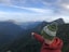 person in orange jacket wearing green knit cap standing on top of mountain during daytime