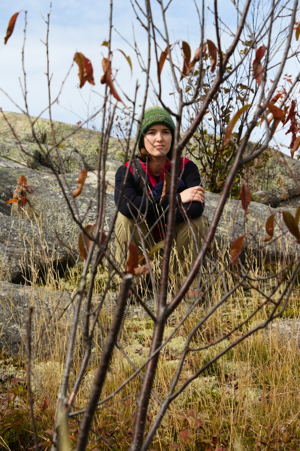 woman in black jacket sitting on brown tree branch during daytime