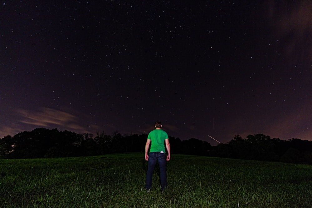 man in red shirt standing on green grass field during night time
