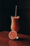 orange juice in clear drinking glass with straw
