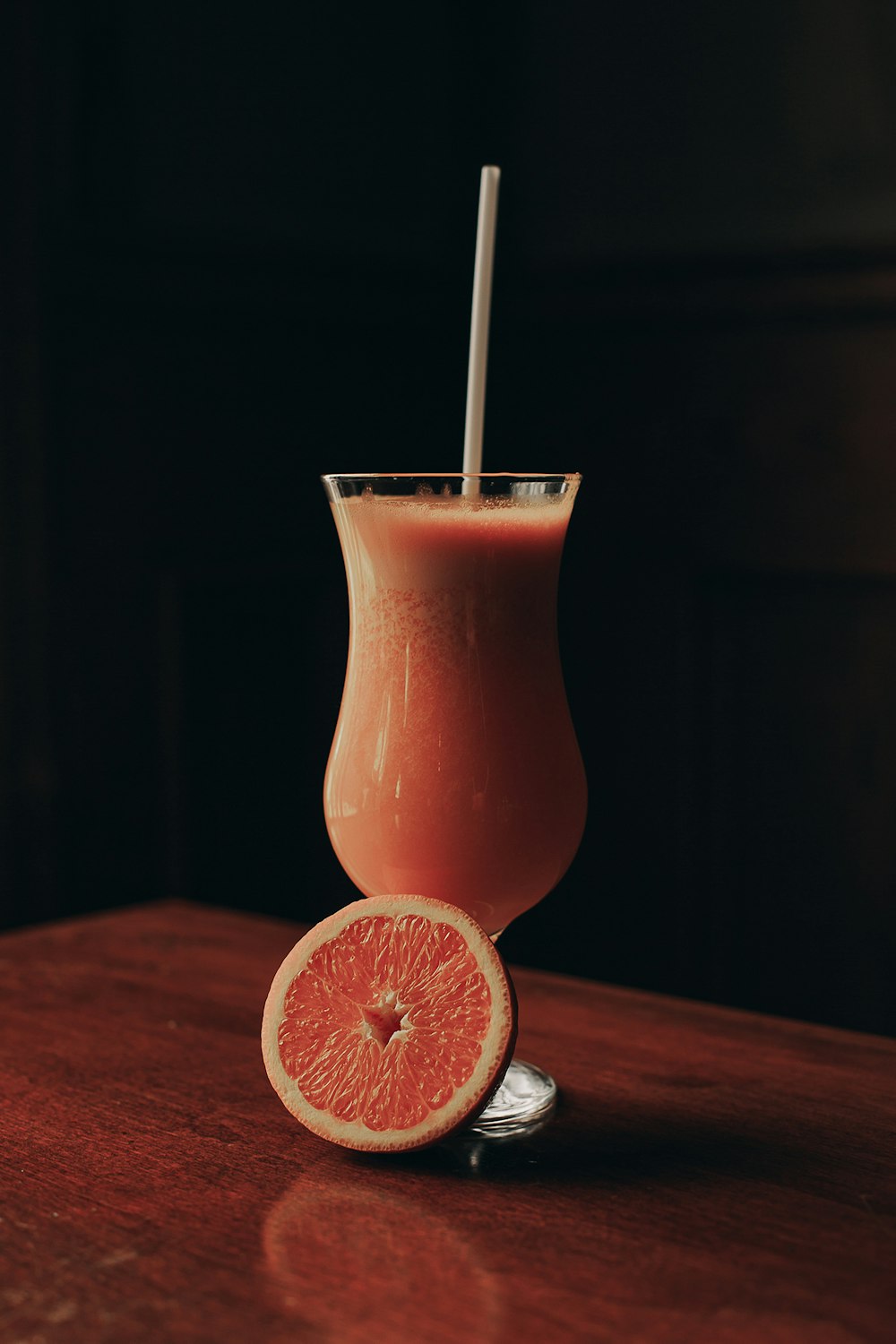 orange juice in clear drinking glass with straw