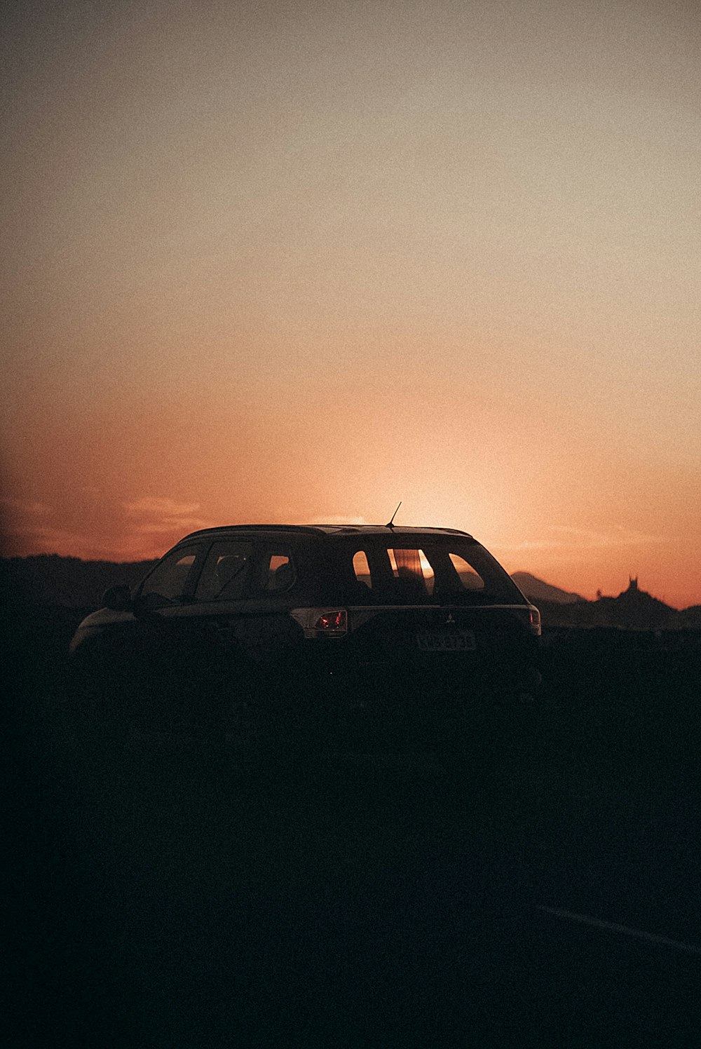 Schwarzer SUV auf grauem Sand bei Sonnenuntergang