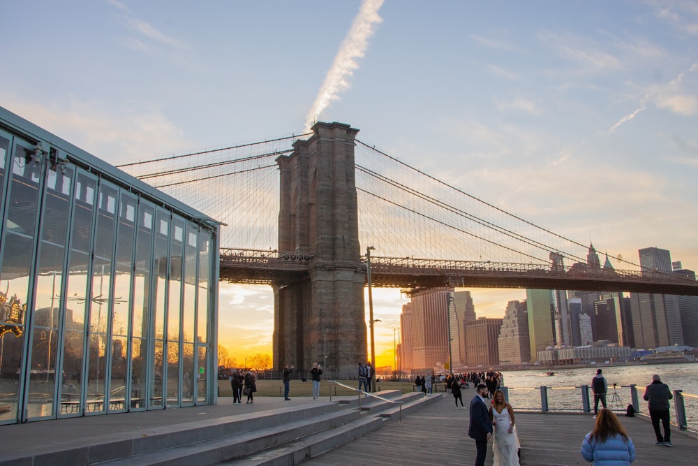 people walking on sidewalk near bridge during daytime