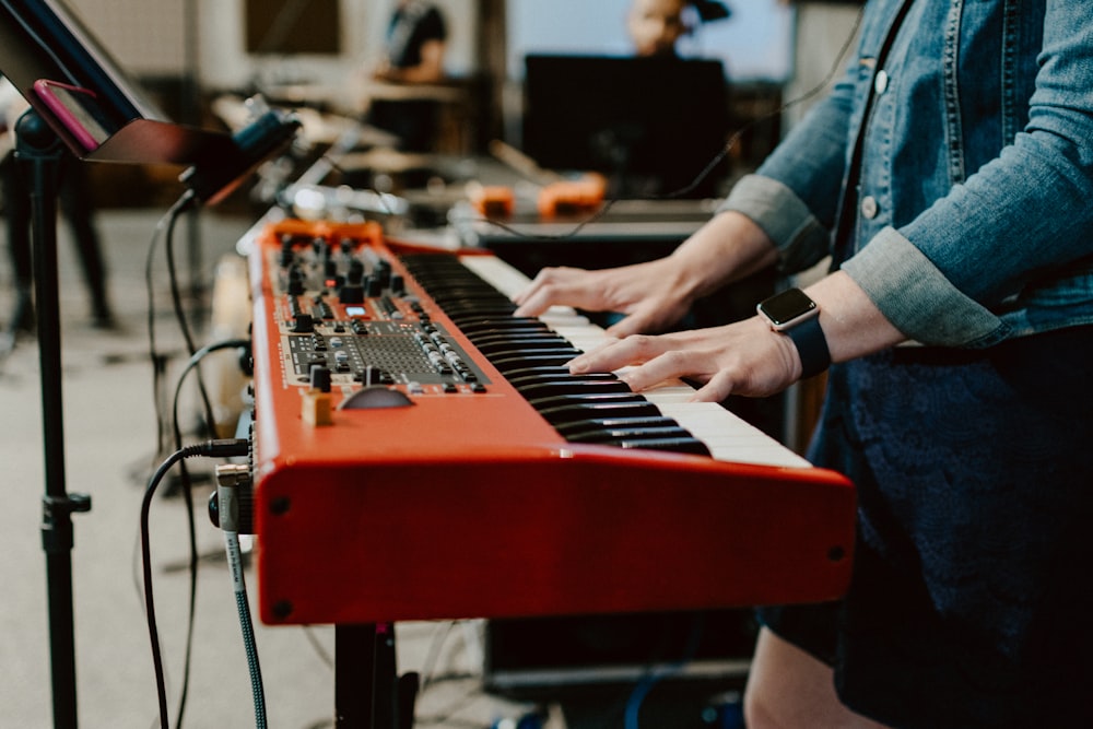 Persona tocando el piano eléctrico rojo y negro