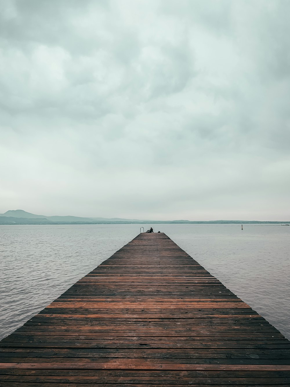 brown wooden dock on sea under white clouds during daytime