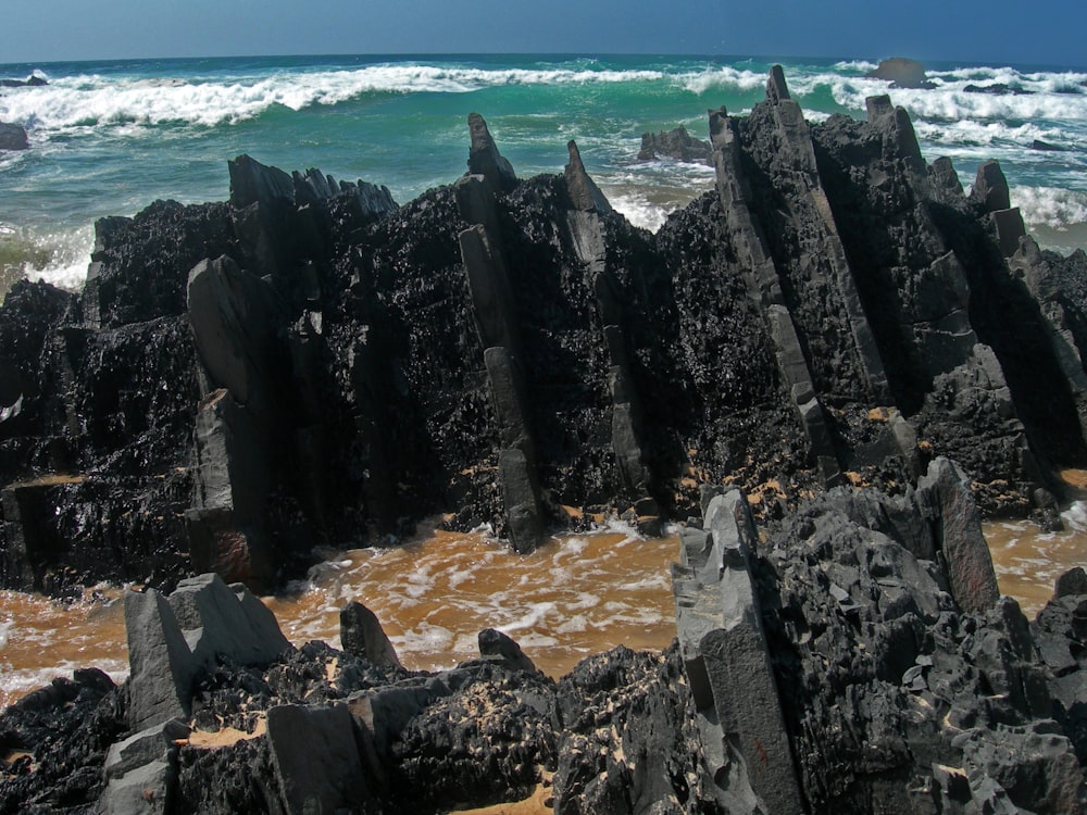 black rock formation near body of water during daytime