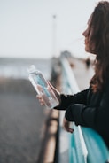 woman in black long sleeve shirt holding white plastic bottle