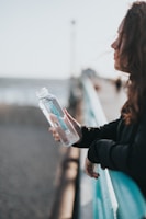 woman in black long sleeve shirt holding white plastic bottle