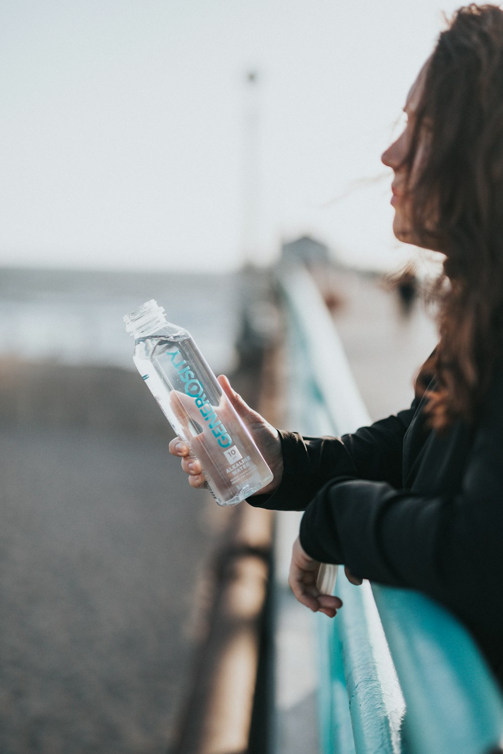 Frau im schwarzen Langarmhemd mit weißer Plastikflasche