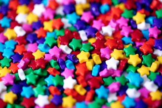 Brightly colored jelly candies shaped like stars and hearts scattered on a white background