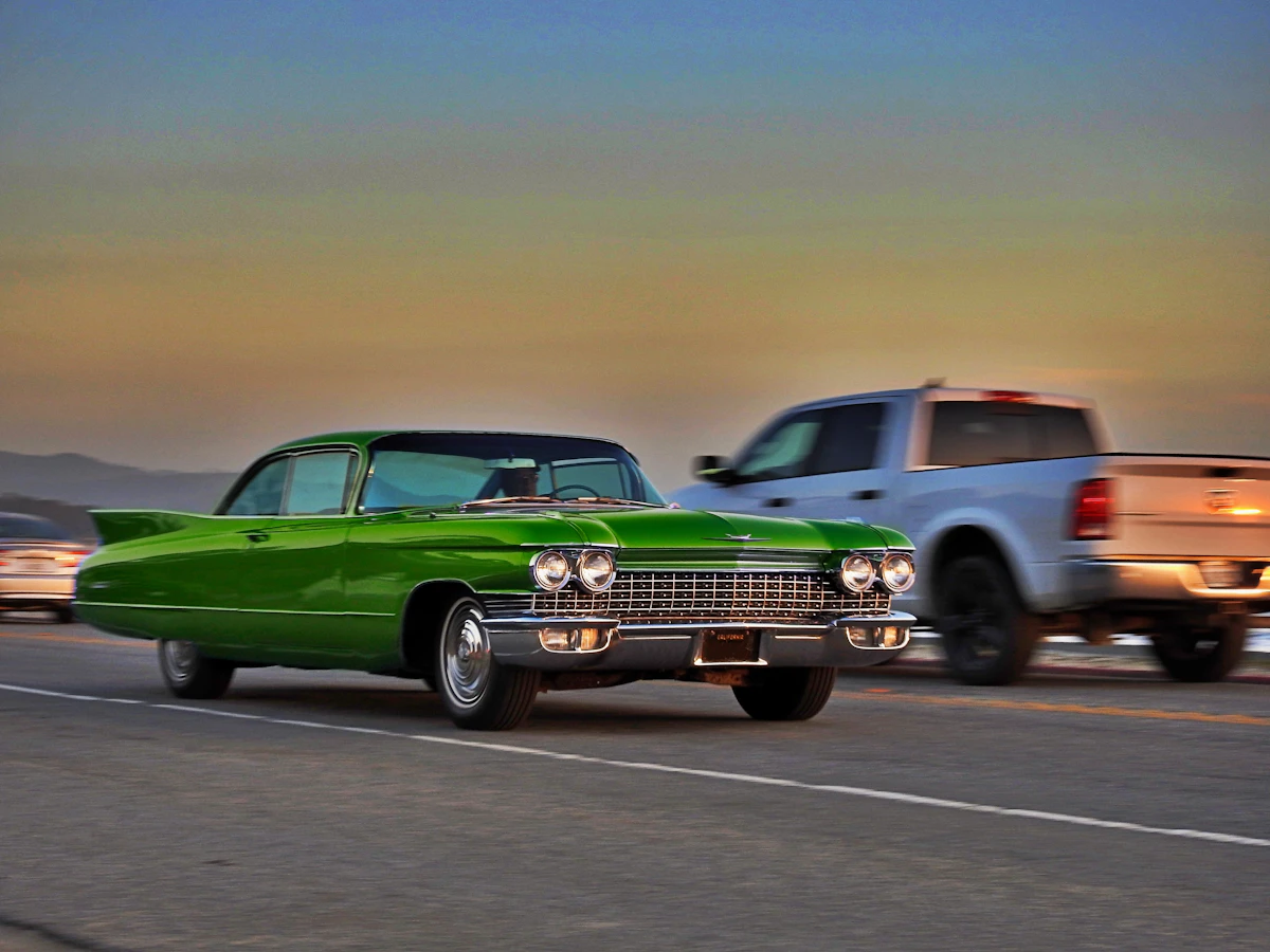 1960 Cadillac DeVille driving on a highway at sunset