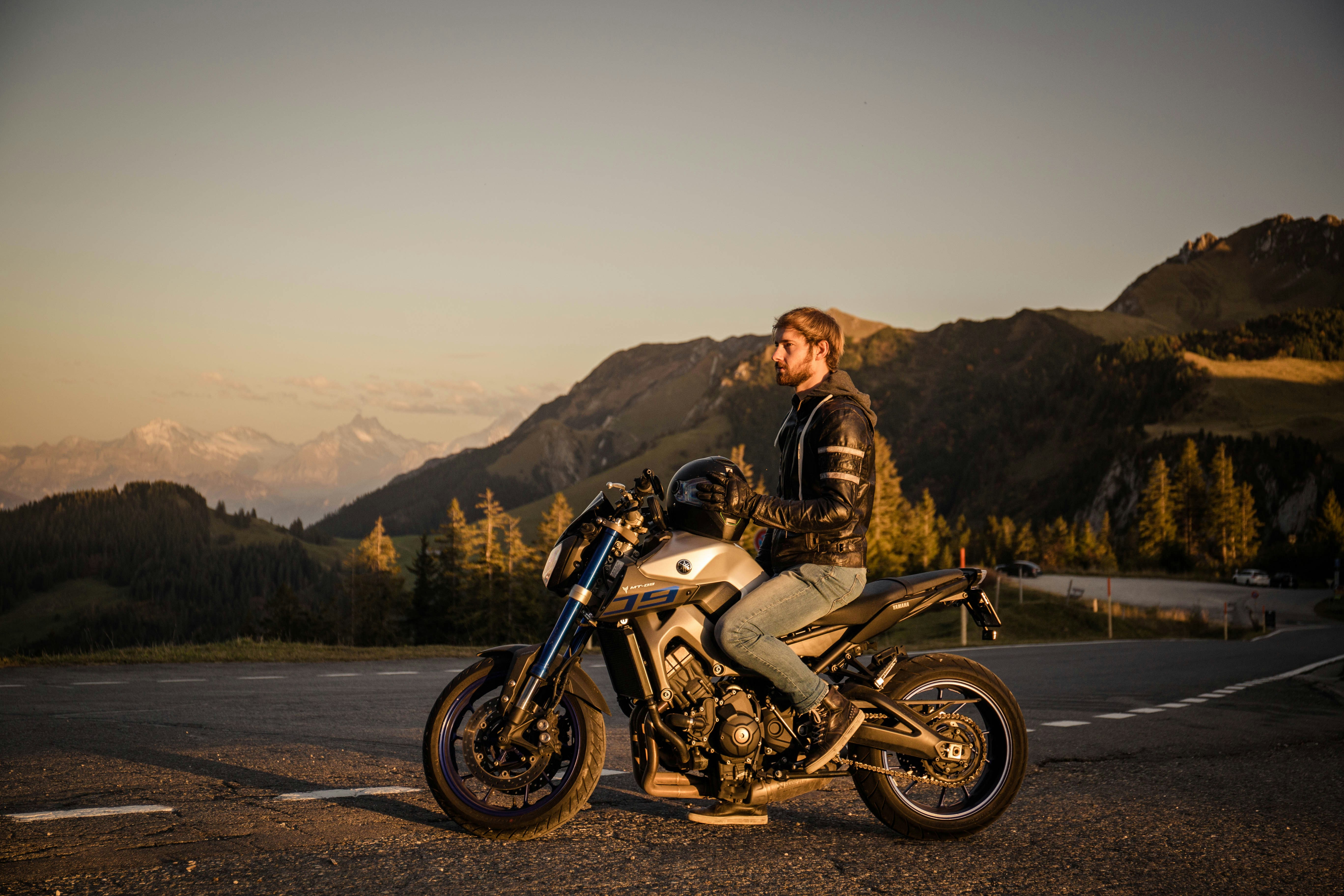 uomo in giacca marrone che cavalca su moto bianca e nera