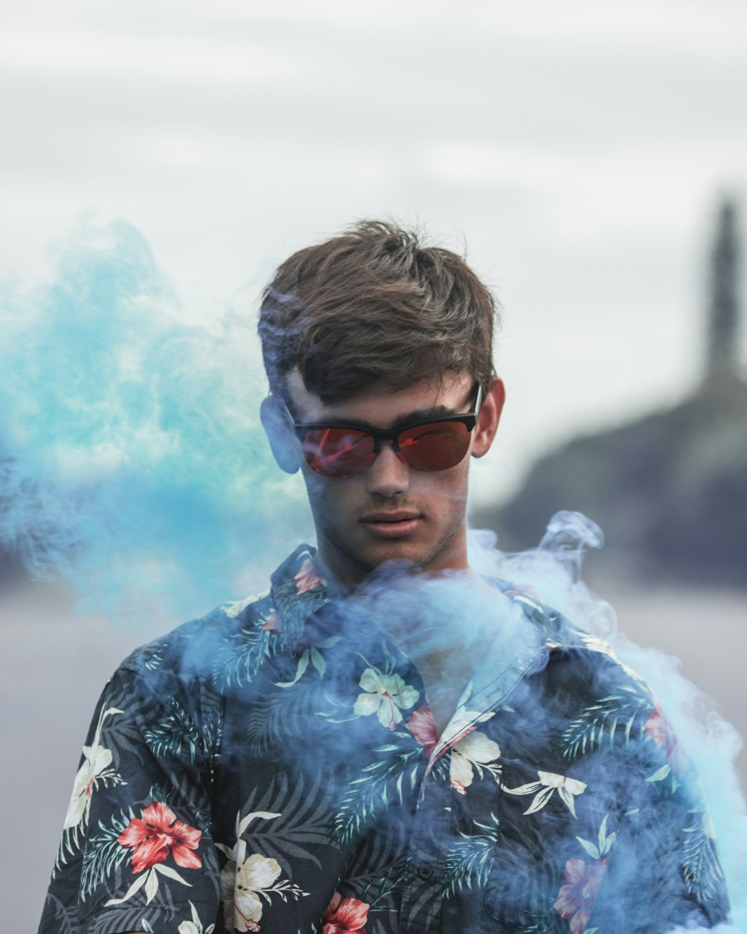 man in blue green and white floral collared shirt with black sunglasses