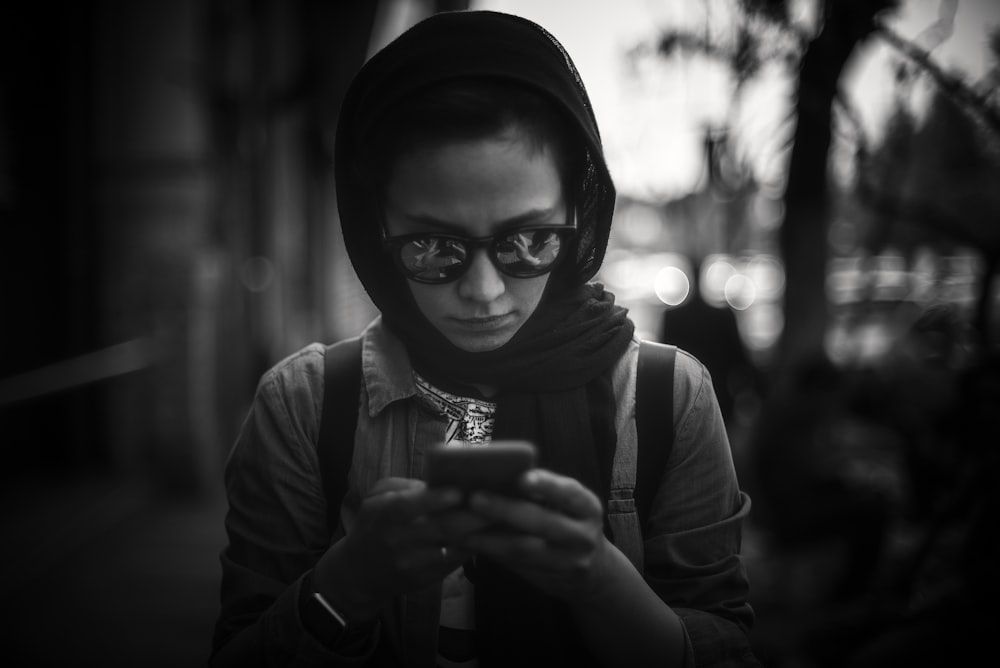 grayscale photo of woman in hijab holding cup