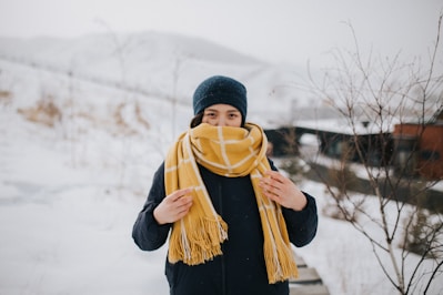 woman in black knit cap and black jacket standing on snow covered ground during daytime