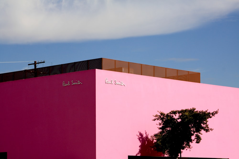 pink concrete building near green tree under blue sky during daytime